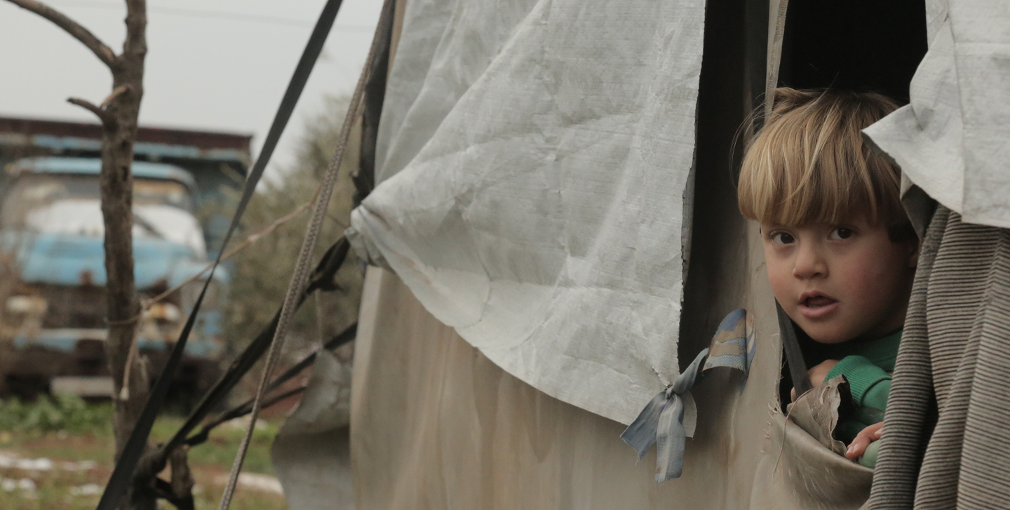 Refugee child looking through tent